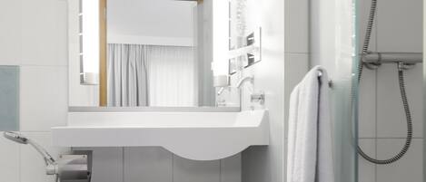 Un baño con lavamanos blanco, espejo y ducha.