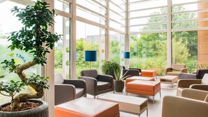 Un interior moderno con ventanas amplias, varias zonas de estar y una planta en maceta.