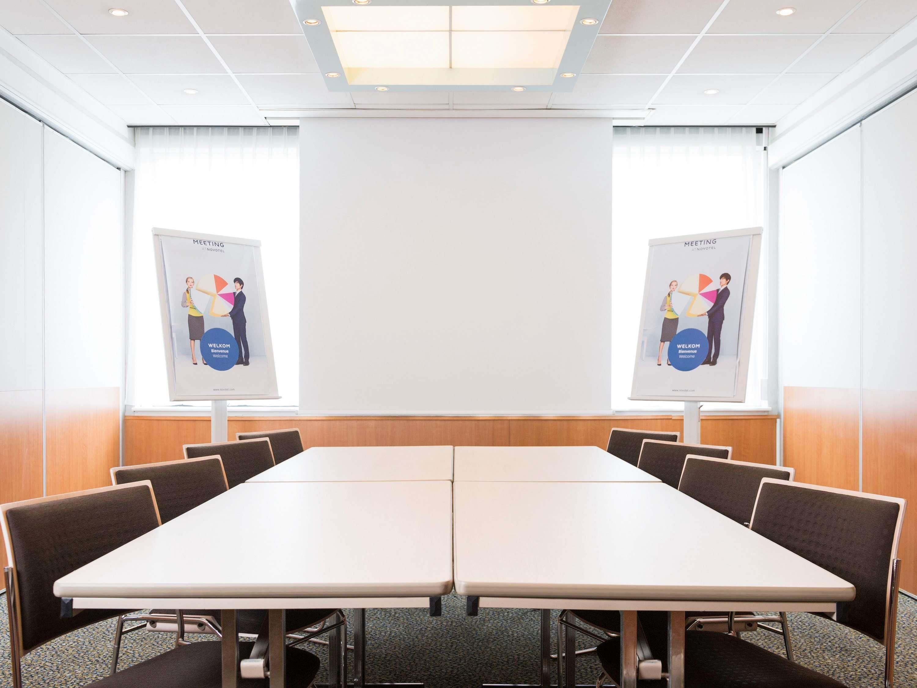 A conference room with a long table, chairs, and two posters on the walls.