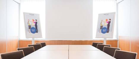 A conference room with a long table, chairs, and two posters on the walls.