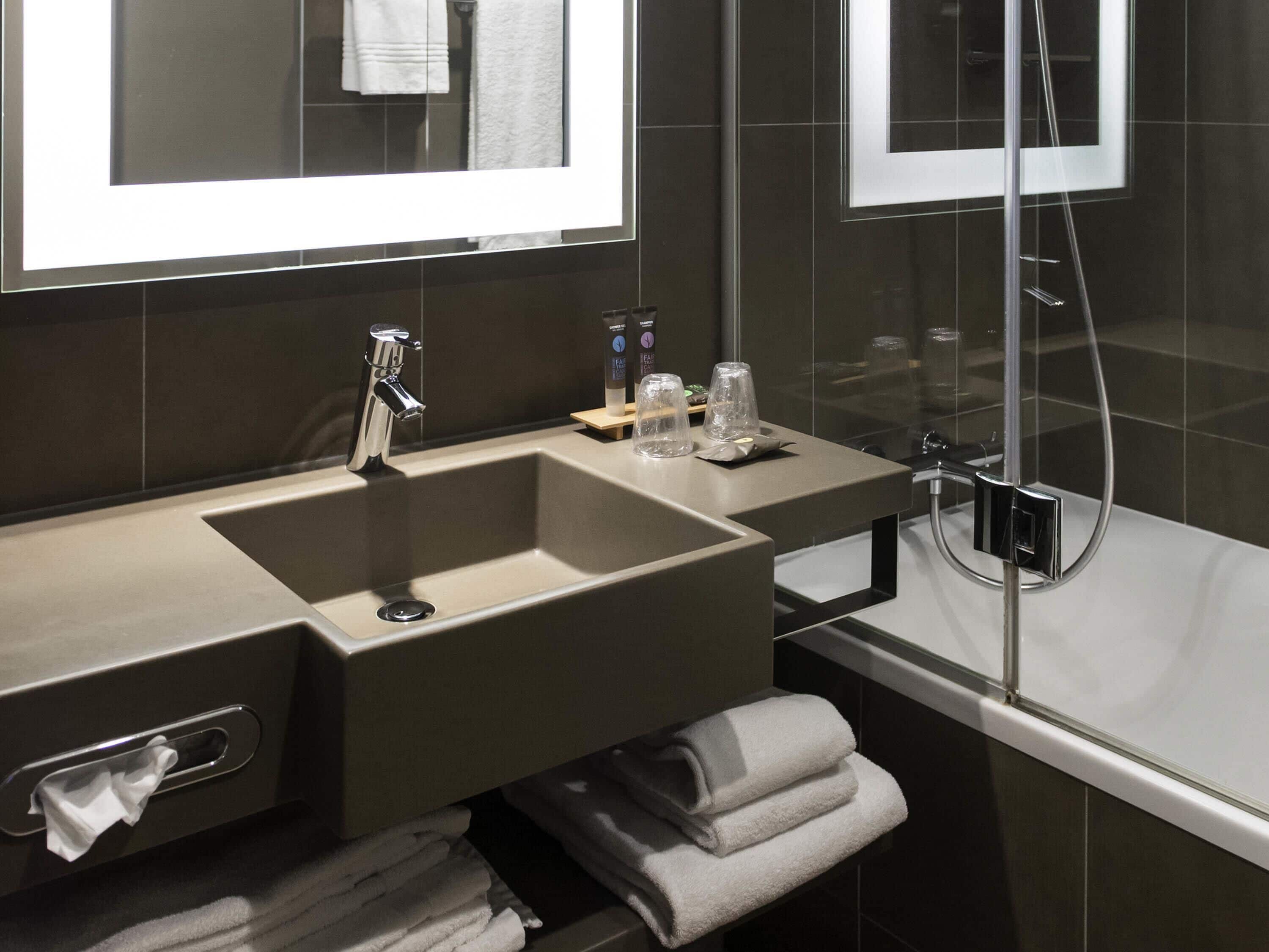 A modern bathroom with a large sink, mirror, and shower.