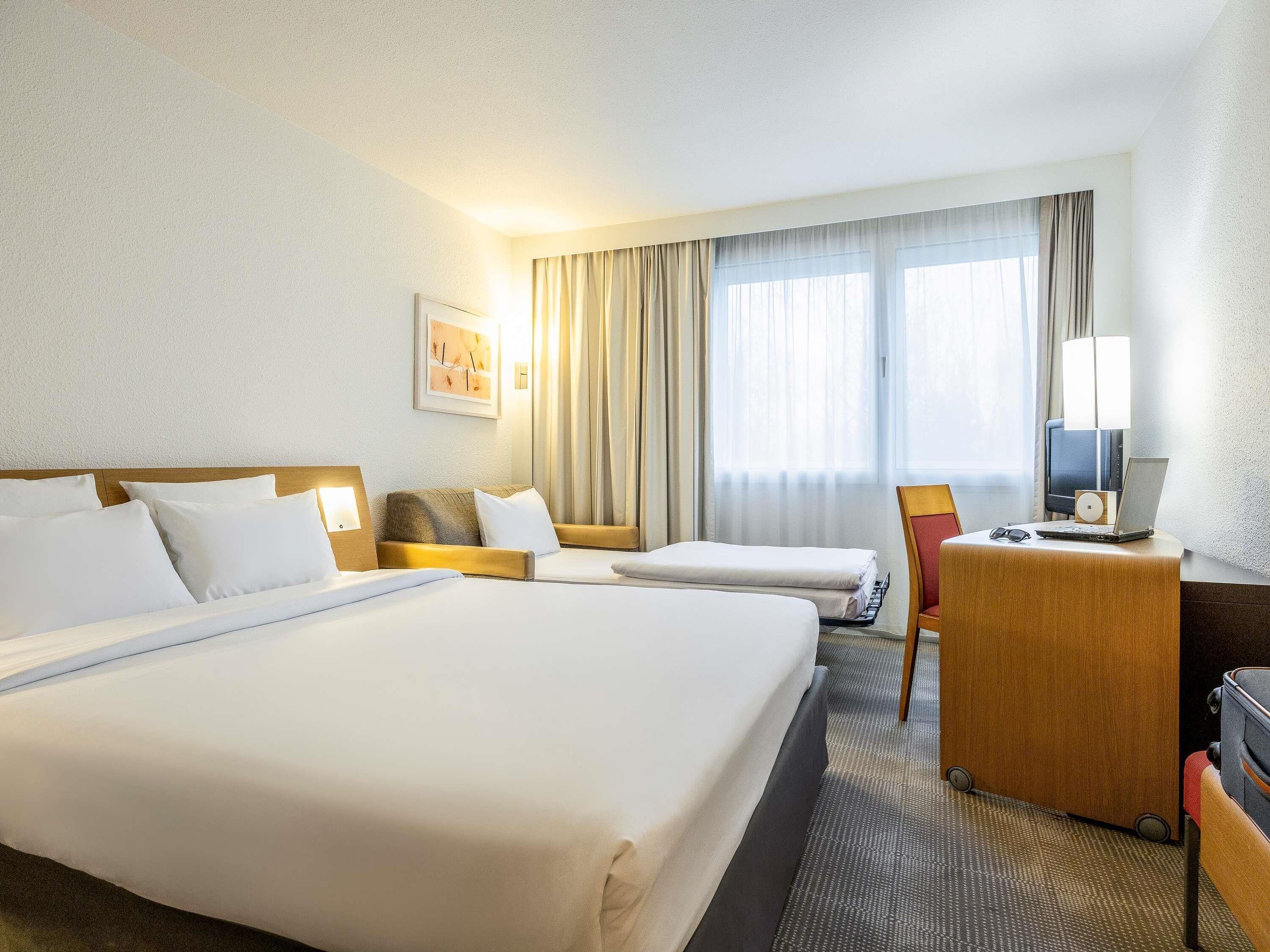 Une chambre d’hôtel avec un grand lit, un bureau avec un ordinateur portable, une chaise et une télévision.
