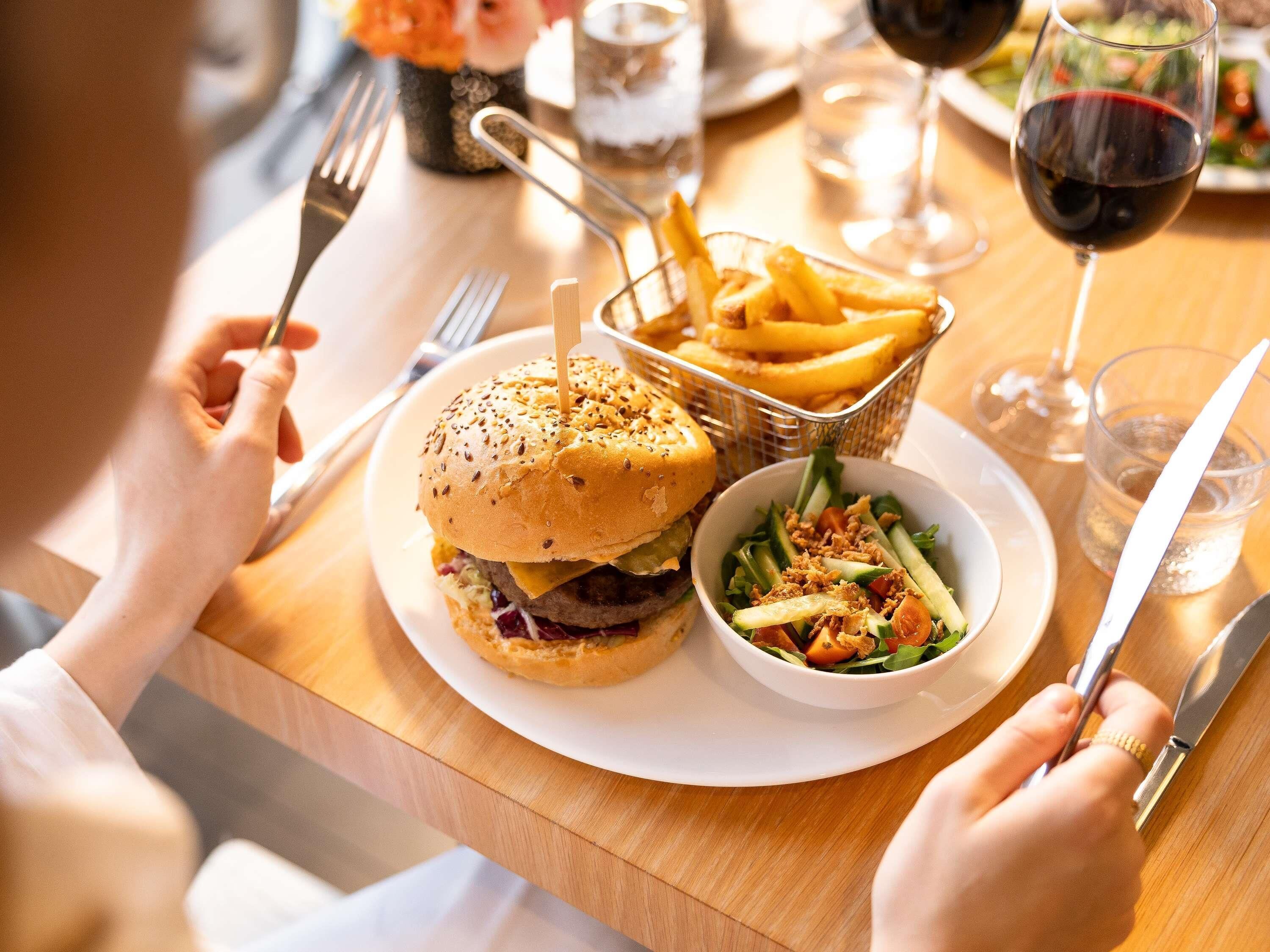 Una mesa de comedor con una hamburguesa, papas fritas y una ensalada.