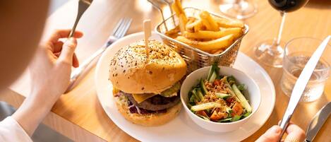 Una mesa de comedor con una hamburguesa, papas fritas y una ensalada.