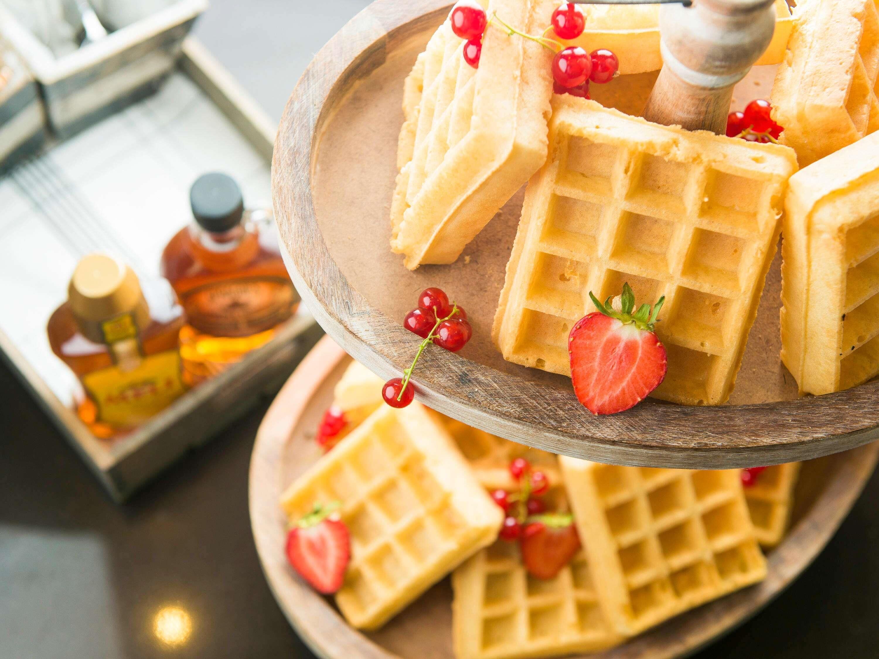 A wooden tray with waffles and strawberries.