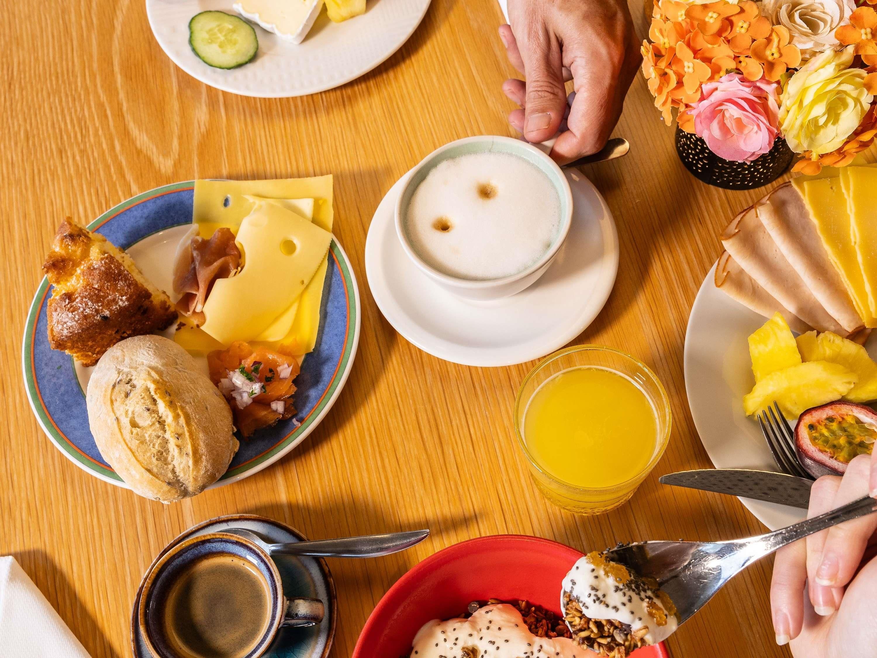 Une table mise pour le petit-déjeuner, avec des assiettes remplies de nourriture, une tasse de café et un verre de jus d’orange.
