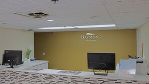 A reception desk with two monitors, a plant, and a sign indicating a Baymont by Wyndham hotel. - Baymont by Wyndham Springfield (Springfield)