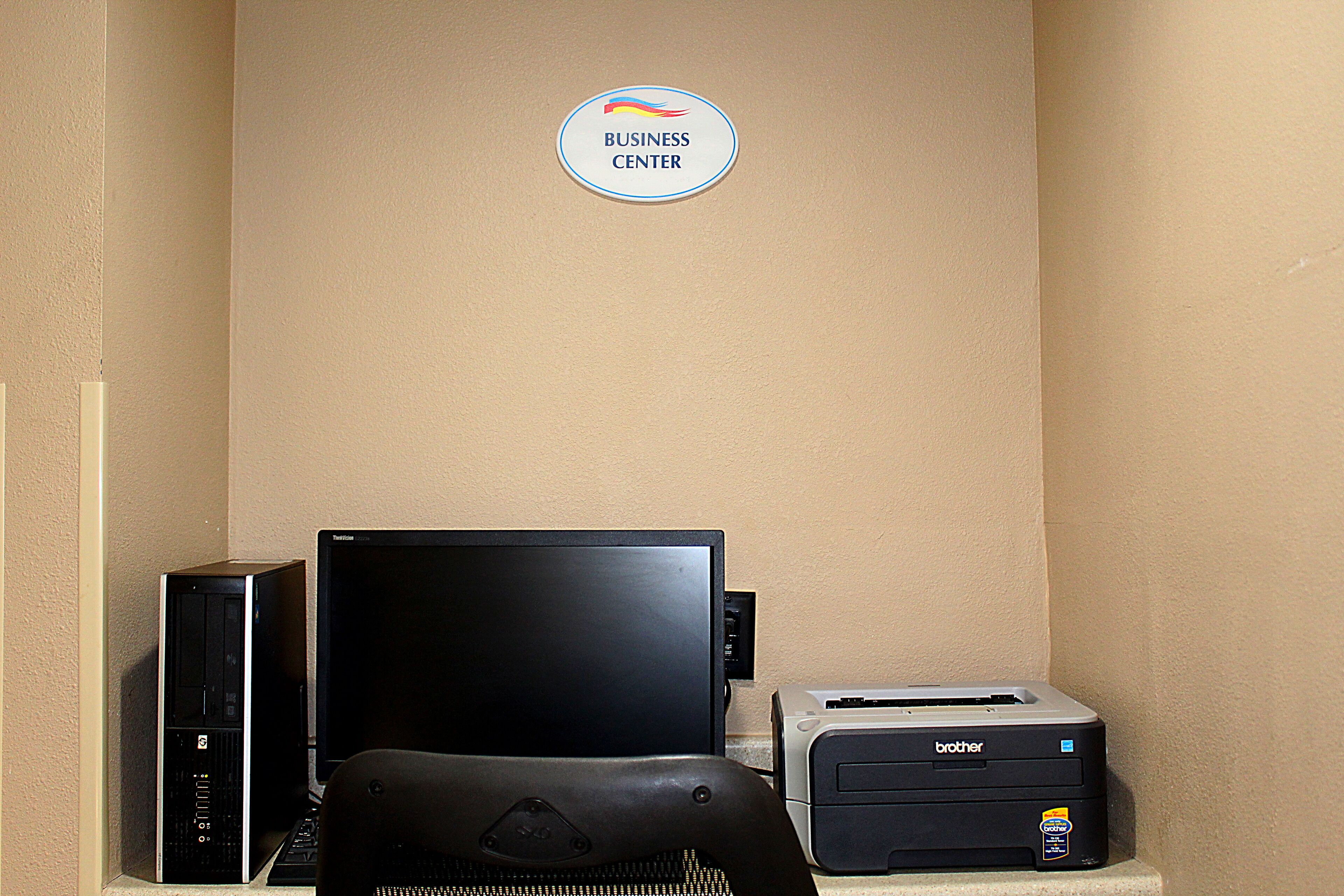 A business center with a desktop computer, a monitor, and a Brother printer.