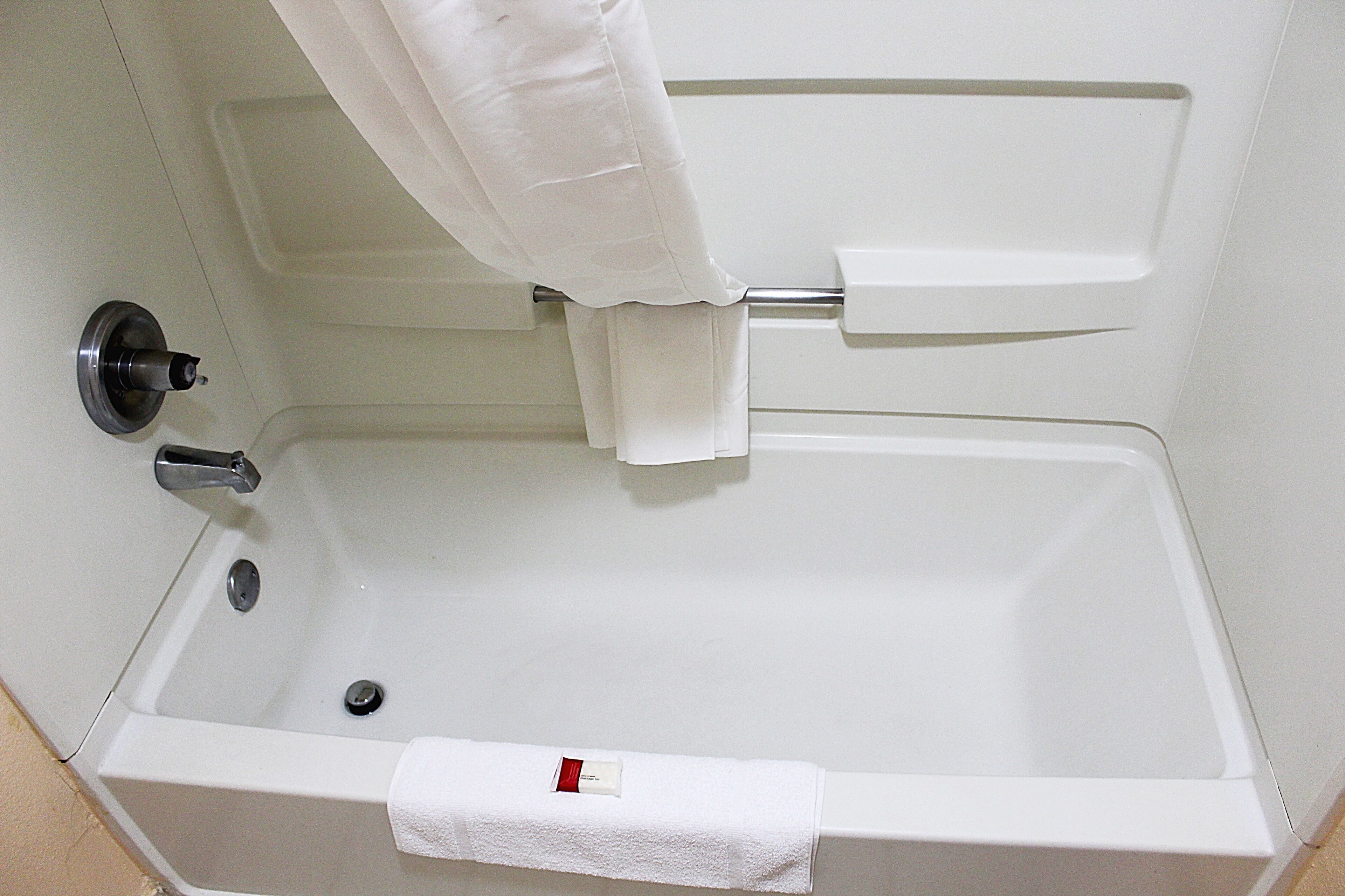 A white bathtub with a towel rack, a faucet, and a drain.