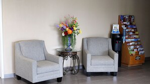 Two grey armchairs, a small round table with a vase of flowers, and a magazine rack. - Baymont by Wyndham Springfield (Springfield)