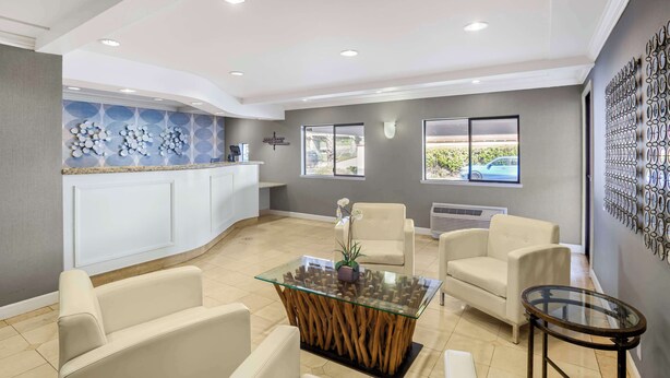 A modern reception area with a glass-top table, beige sofas, and a white counter. - Best Western Inn (Santa Cruz)