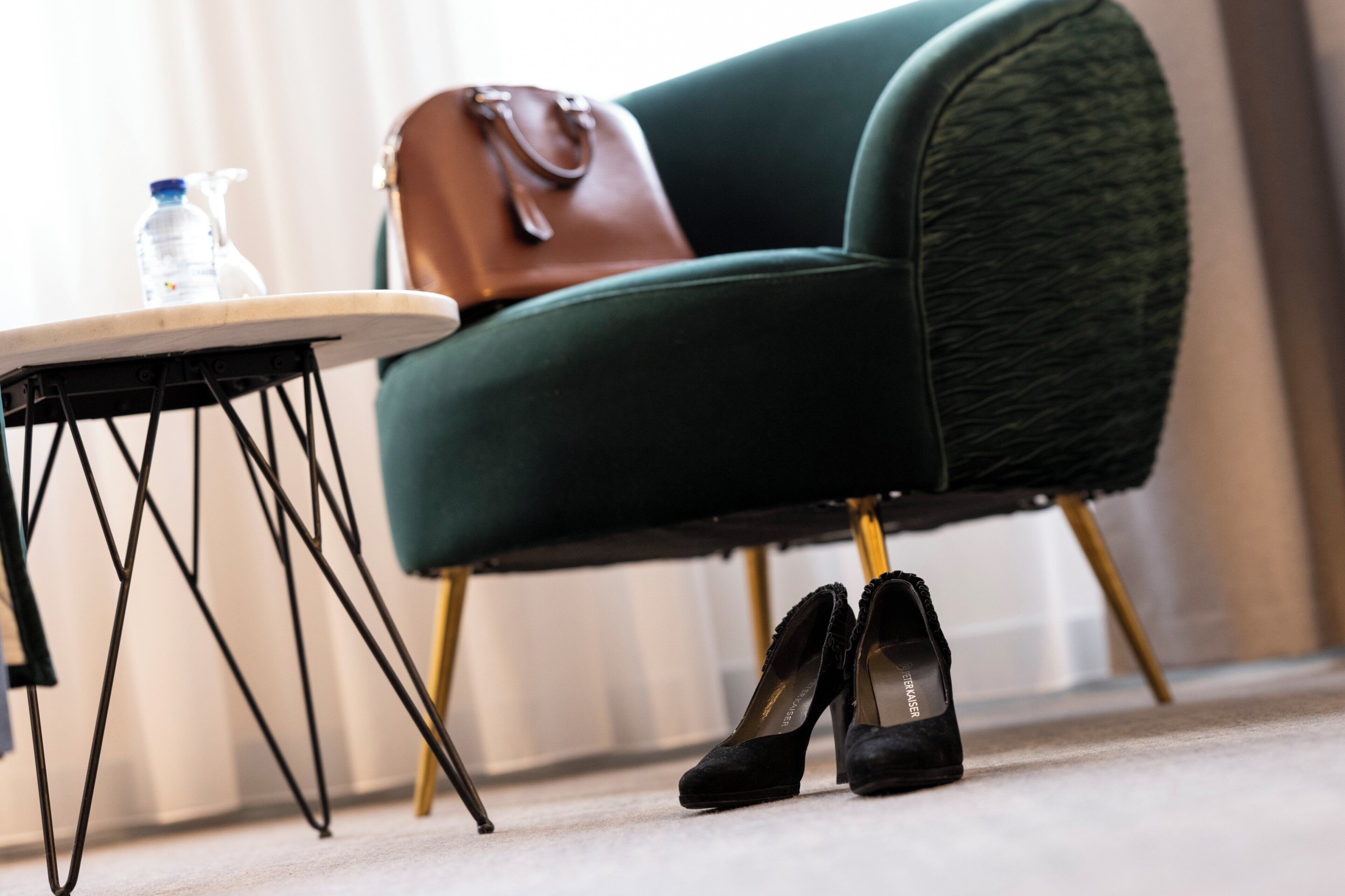 Une chaise avec un sac à main, une paire de chaussures et une bouteille posés sur une petite table.