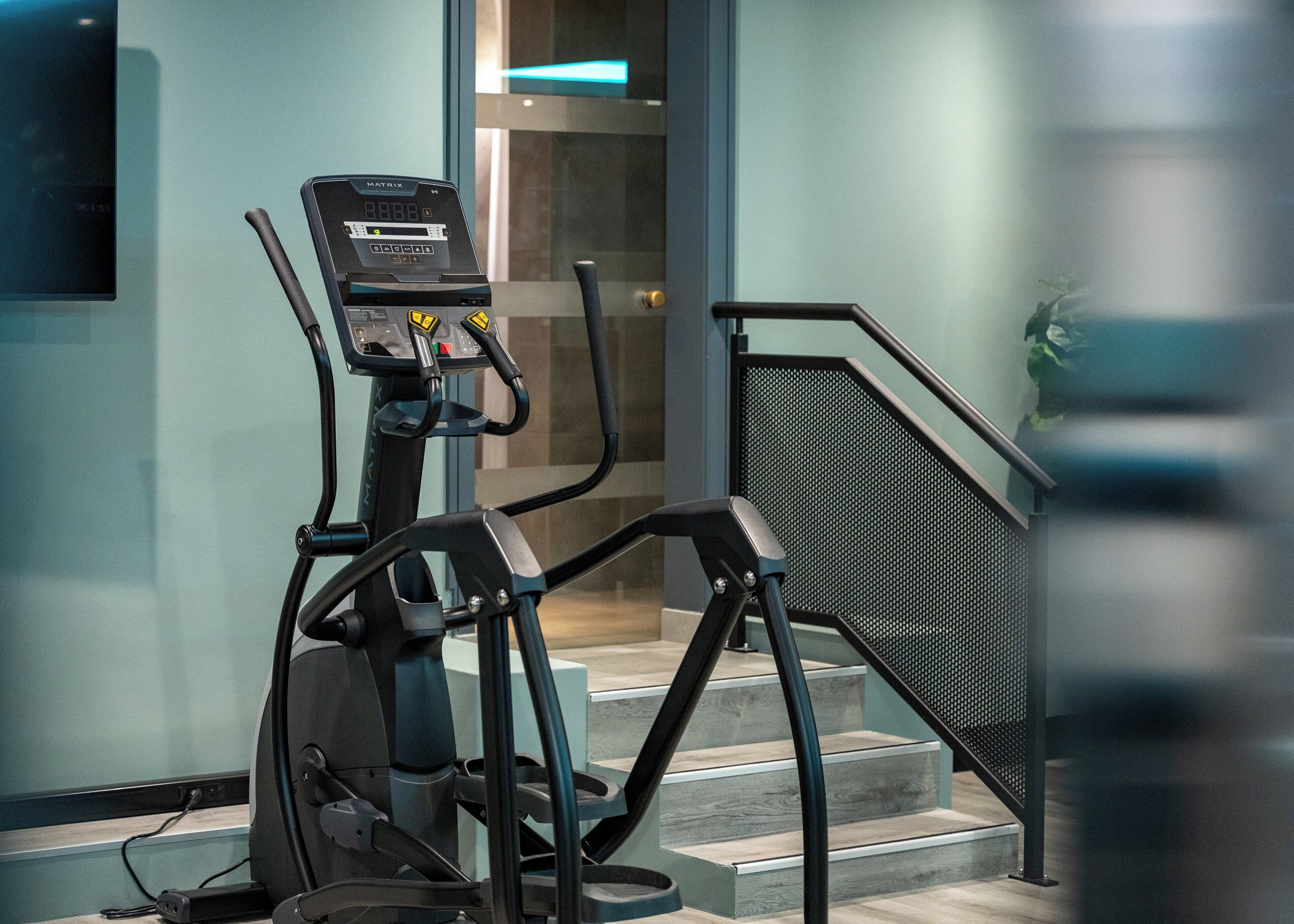 An exercise machine in a modern indoor setting with a staircase and a glass door in the background.
