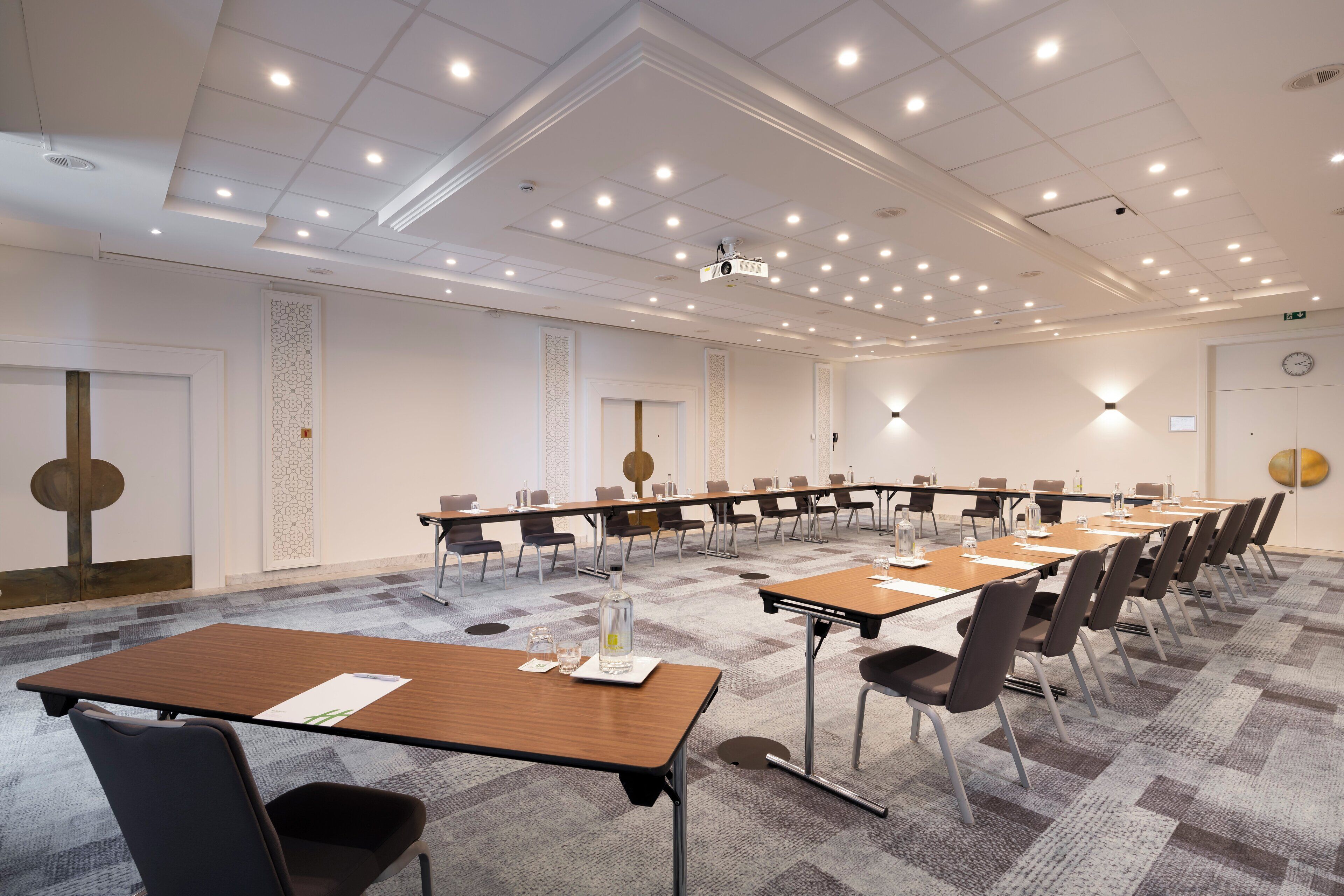 Une salle de conférence avec une longue table, de nombreuses chaises et un projecteur fixé au plafond.