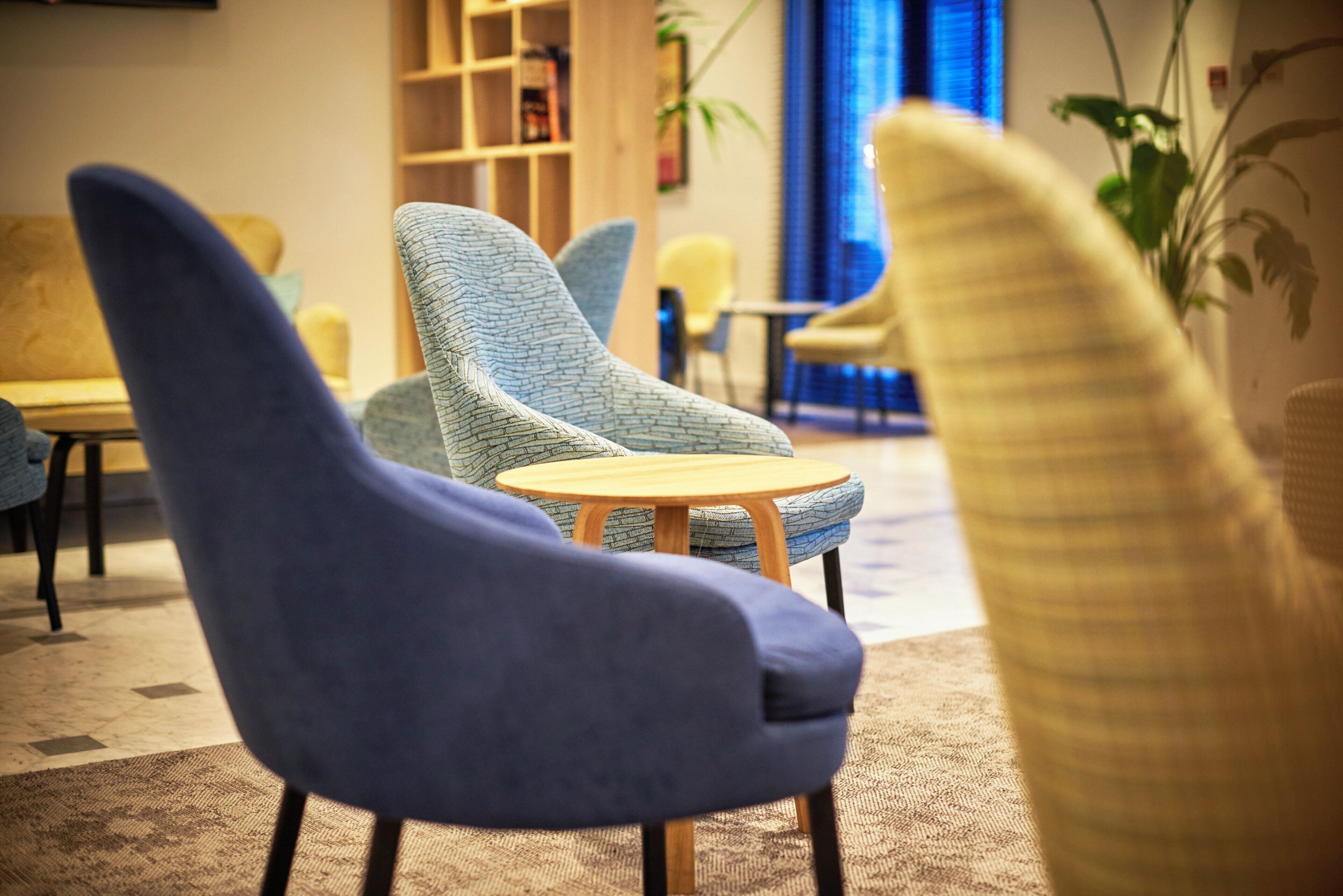 Un espace de détente moderne avec des sièges confortables, une petite table ronde et une bibliothèque en arrière-plan.
