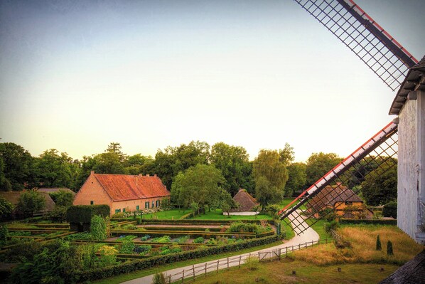 A traditional windmill, a thatched-roof house, and a well-maintained garden with a pathway. - Holiday Inn Hasselt by IHG (Hasselt)