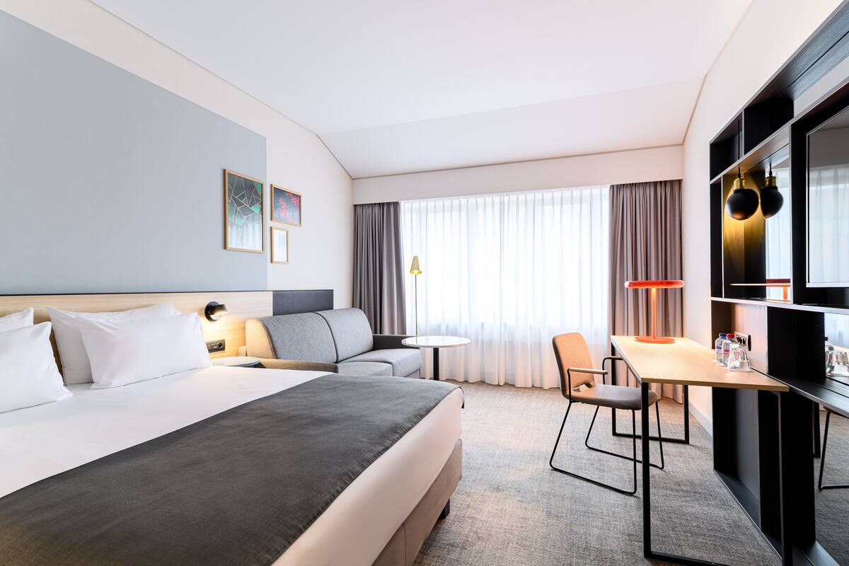 Een hotelkamer met een groot bed, een bank, een bureau en een televisie.