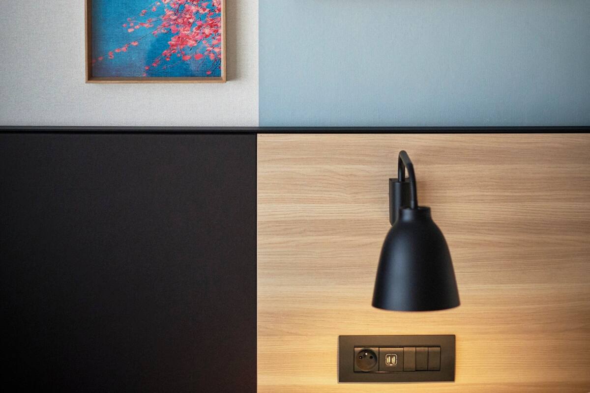 Een moderne kamer met een houten kast, een zwarte lamp en een schilderij van kersenbloesems.