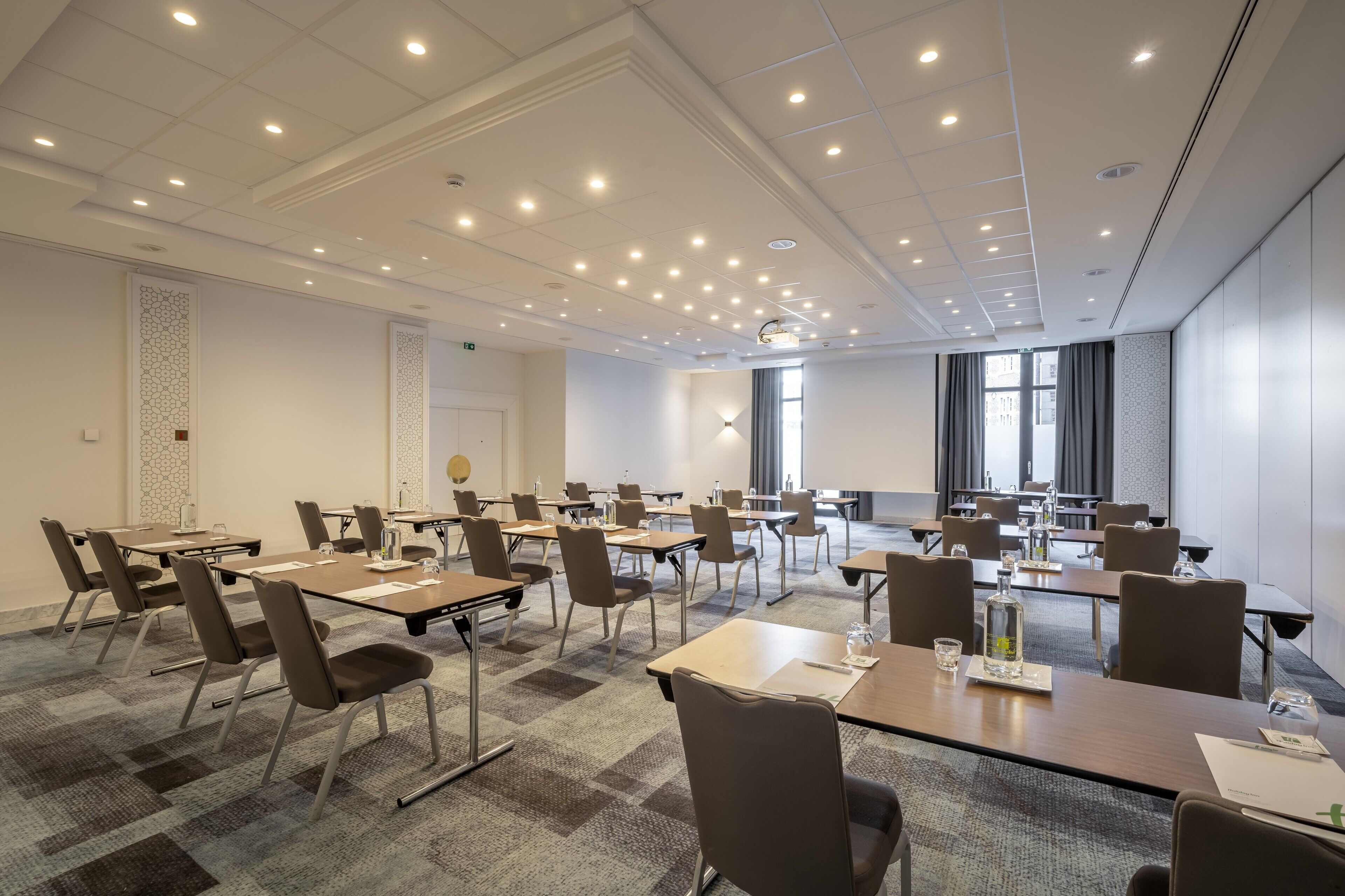 A conference room with multiple tables and chairs, equipped with nameplates and water bottles.