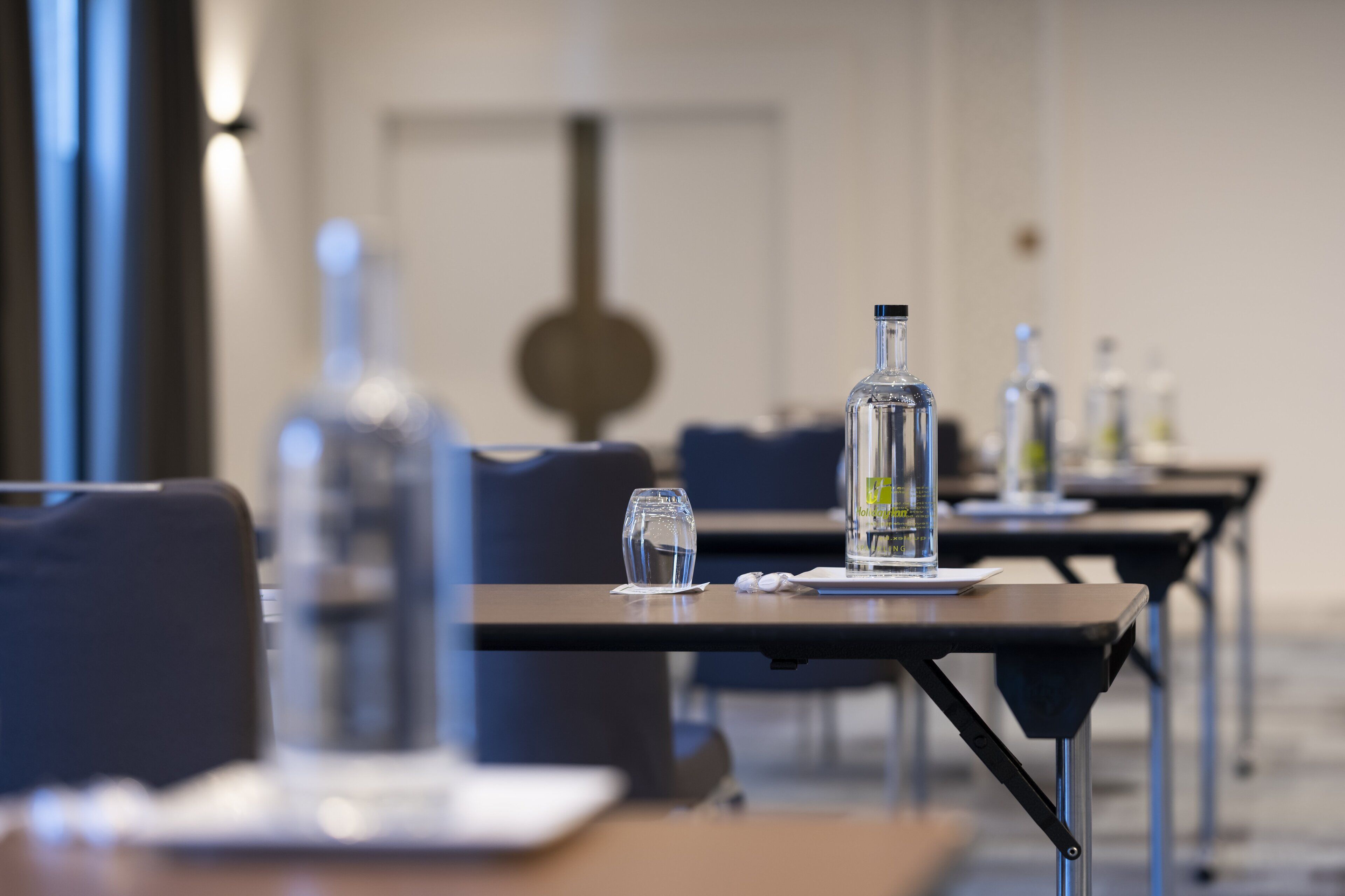 A conference room with tables, chairs, and water bottles.
