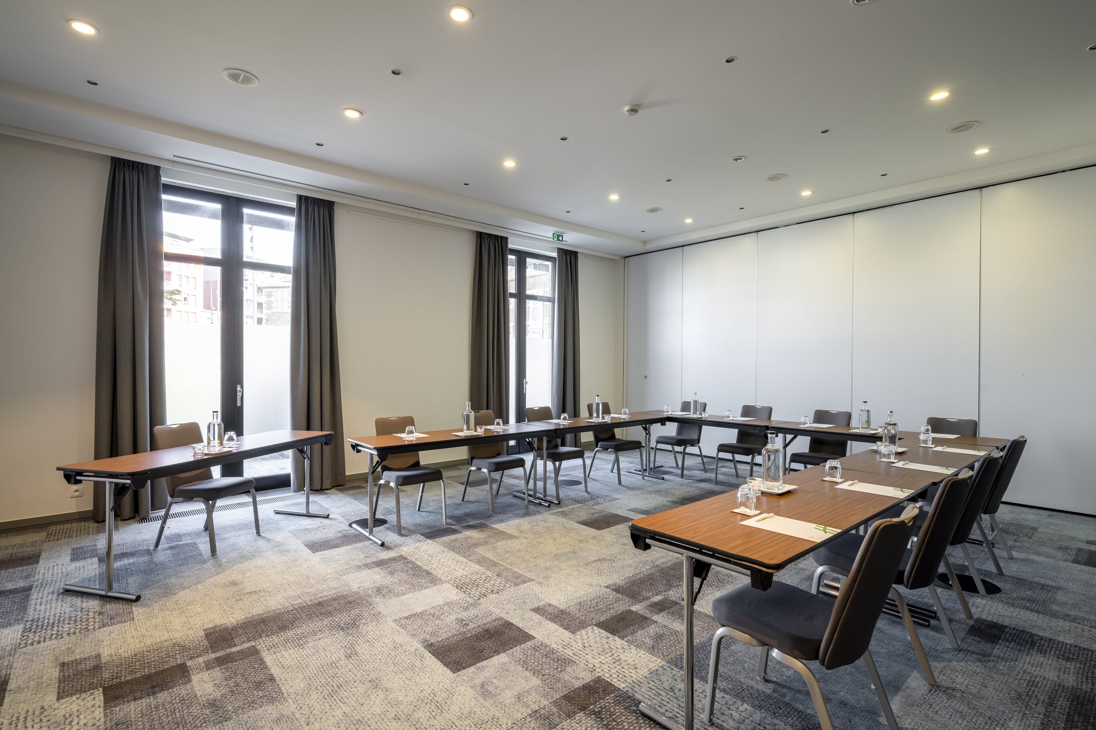 A conference room with a long table, chairs, and a carpeted floor.