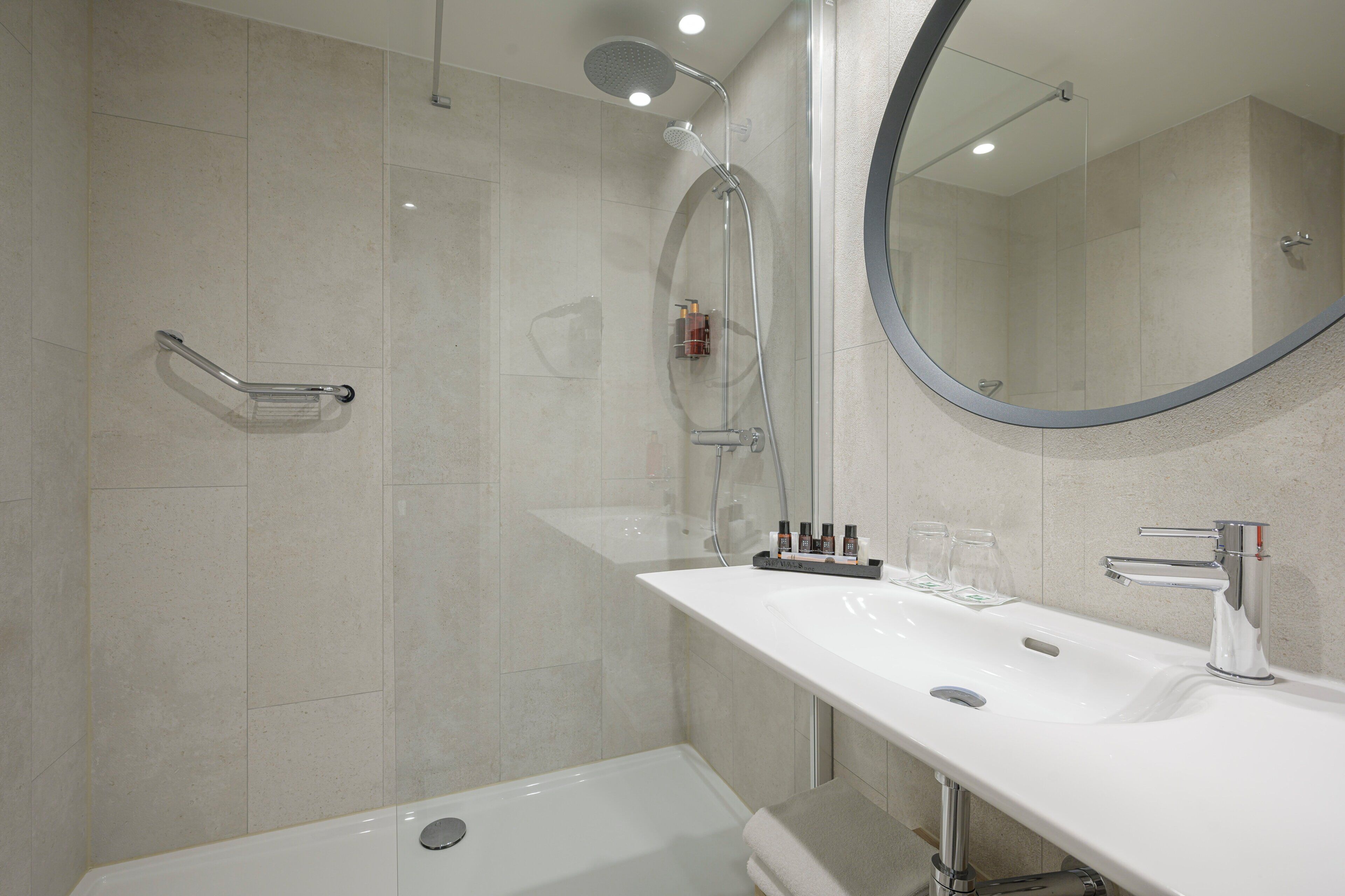 A modern bathroom with a bathtub, a shower with a glass door, a vanity with a sink, and a mirror.