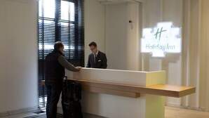 A reception desk with a digital screen displaying "Holiday Inn" in a hotel lobby.