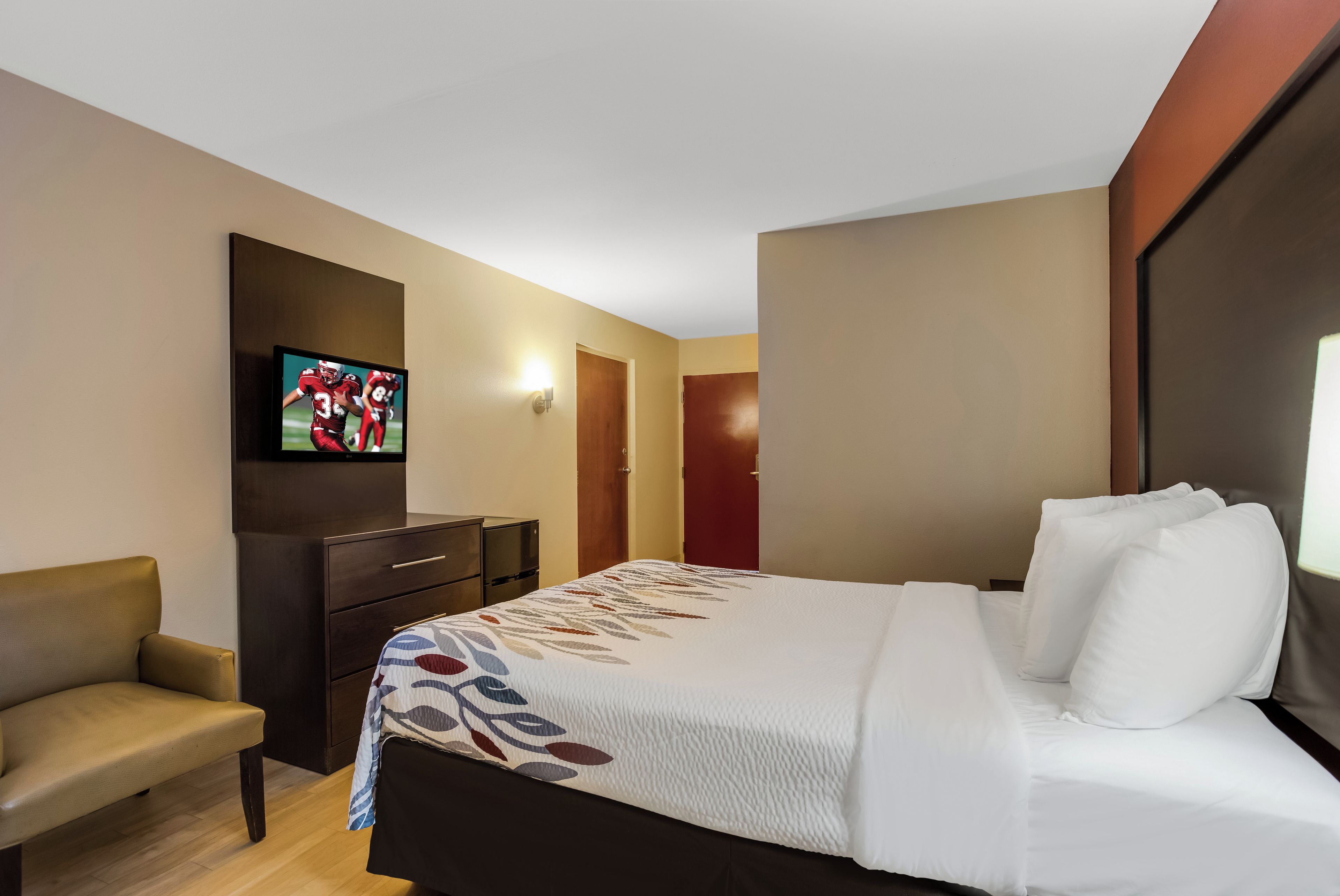 A hotel room with a bed, a television, a desk, and a chair.