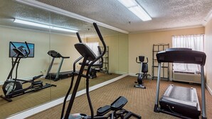 Ein Fitnessraum mit Trainingsgeräten, darunter Laufbänder, ein Crosstrainer und ein Ergometer.