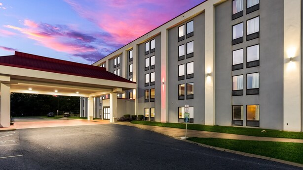 Um hotel moderno com entrada coberta, vários andares e fachada bem iluminada.