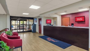 A reception area with a reception desk, red chairs, a blue mat with 'Rooftop Inn' text, and a 'Free Wi-Fi All Rooms' sign. - Red Roof Inn Nashville - Music City (Nashville)