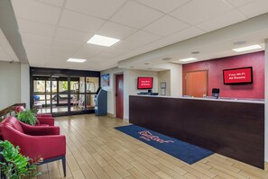 A reception area with a reception desk, red chairs, a blue mat with 'Rooftop Inn' text, and a 'Free Wi-Fi All Rooms' sign. - Red Roof Inn Nashville - Music City (Nashville)