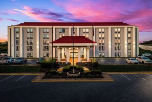 A multi-story building with a red roof, a parking lot, and a landscaped area with a fountain. - Red Roof Inn Nashville - Music City (Nashville)