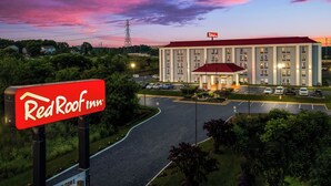 Ein Red Roof Inn mit rotem Dach, einem Parkplatz und blauem Himmel.