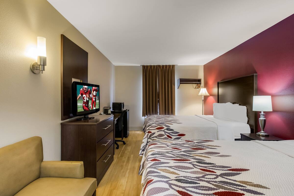 A hotel room with a bed, a TV, a desk, and a chair.
