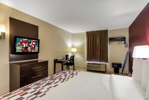 A hotel room with a bed, a desk, a chair, a television, and an air conditioning unit. - Red Roof Inn Nashville - Music City (Nashville)