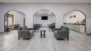 Amplia habitación con dos sofás, una mesita y una zona de cocina con armarios y encimera.