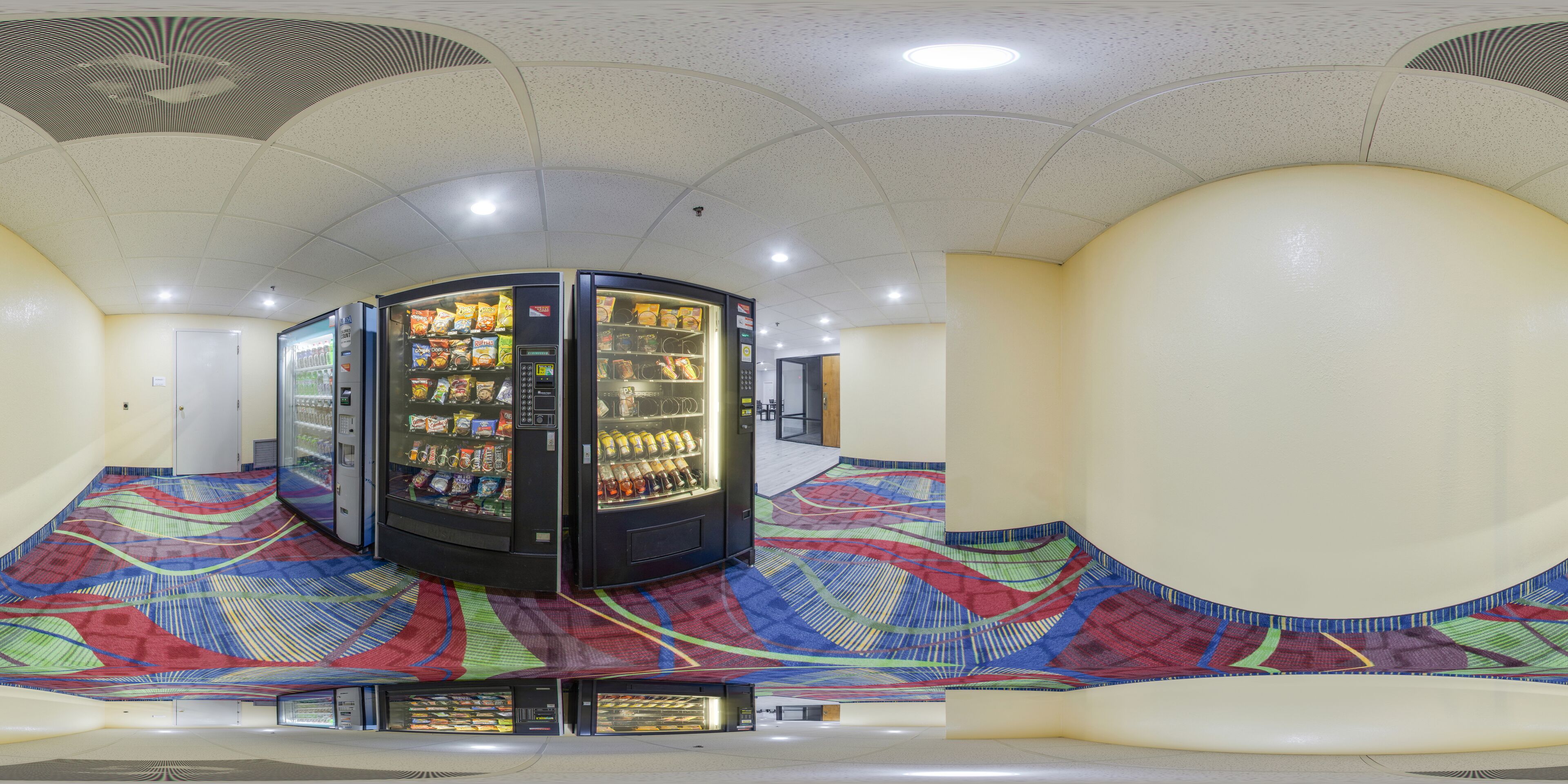 A vending machine area with multiple machines, a patterned floor, and a ceiling with recessed lighting.