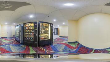 A vending machine area with multiple machines, a patterned floor, and a ceiling with recessed lighting.