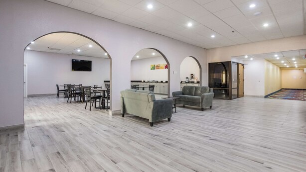 Amplio espacio interior con piso de madera, varios sofás, una mesa de comedor con sillas y una cocina al fondo.