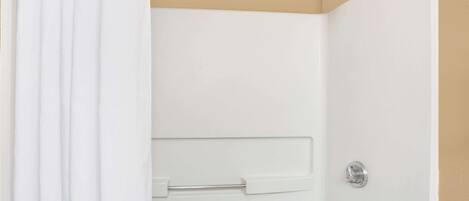 Ducha blanca con grifo plateado y pared beige.