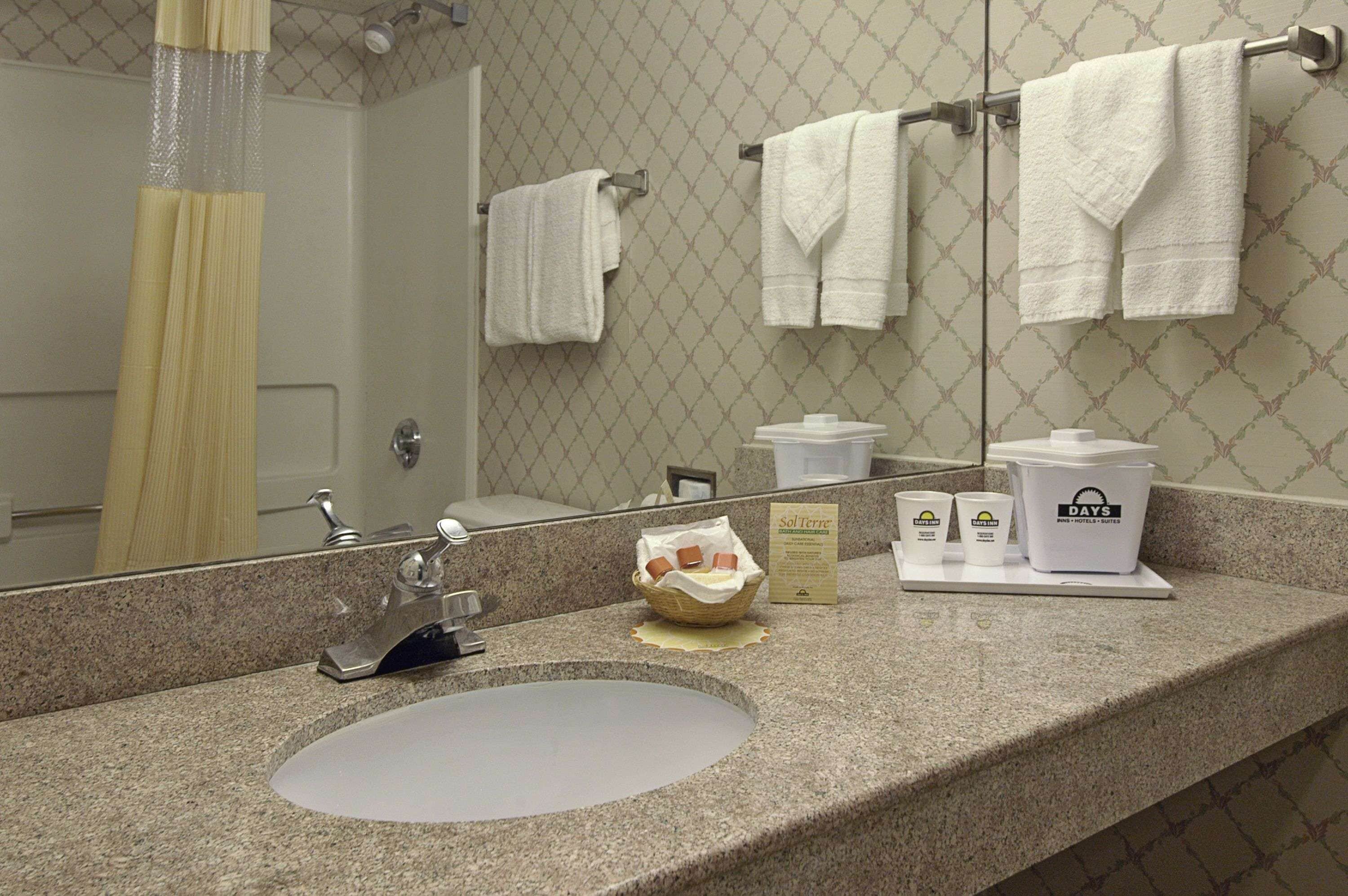 A bathroom with a sink, mirror, and towel rack.