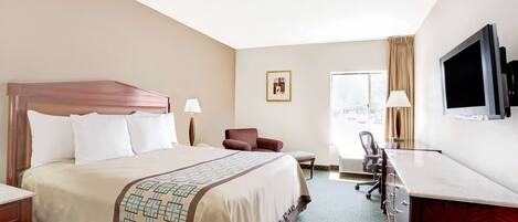 A hotel room with a large bed, a desk, a chair, a television, and a window.