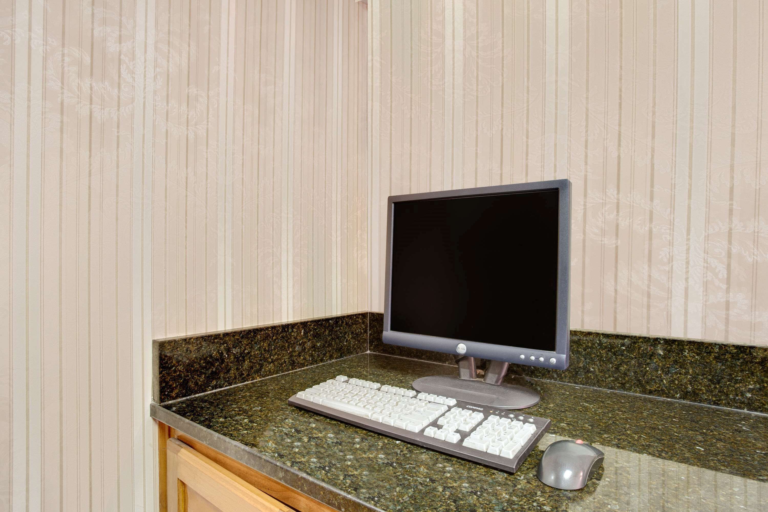 A desktop computer with a keyboard and mouse on a granite countertop.