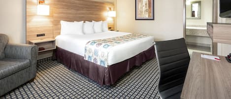 Una habitación de hotel con una cama grande, dos mesitas de noche, un escritorio, una silla y un televisor.