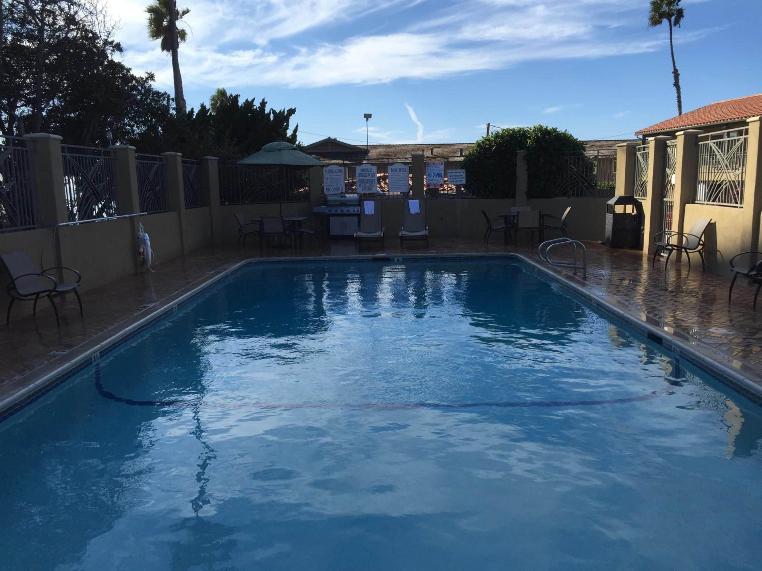 A swimming pool with lounge chairs and a barbecue area.
