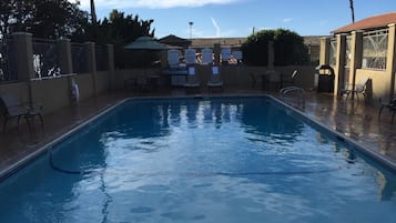 A swimming pool with lounge chairs and a barbecue area.