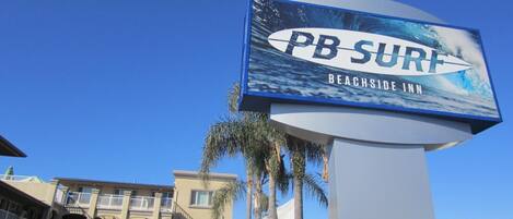 A sign for PB SURF Beachside Inn with a surfboard graphic.