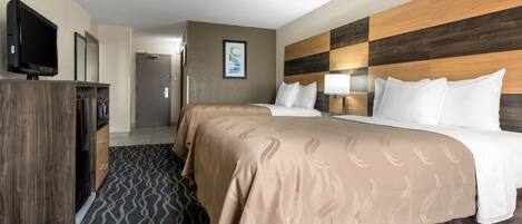 Une chambre d’hôtel avec deux lits, une télévision, une armoire et une porte de salle de bain.