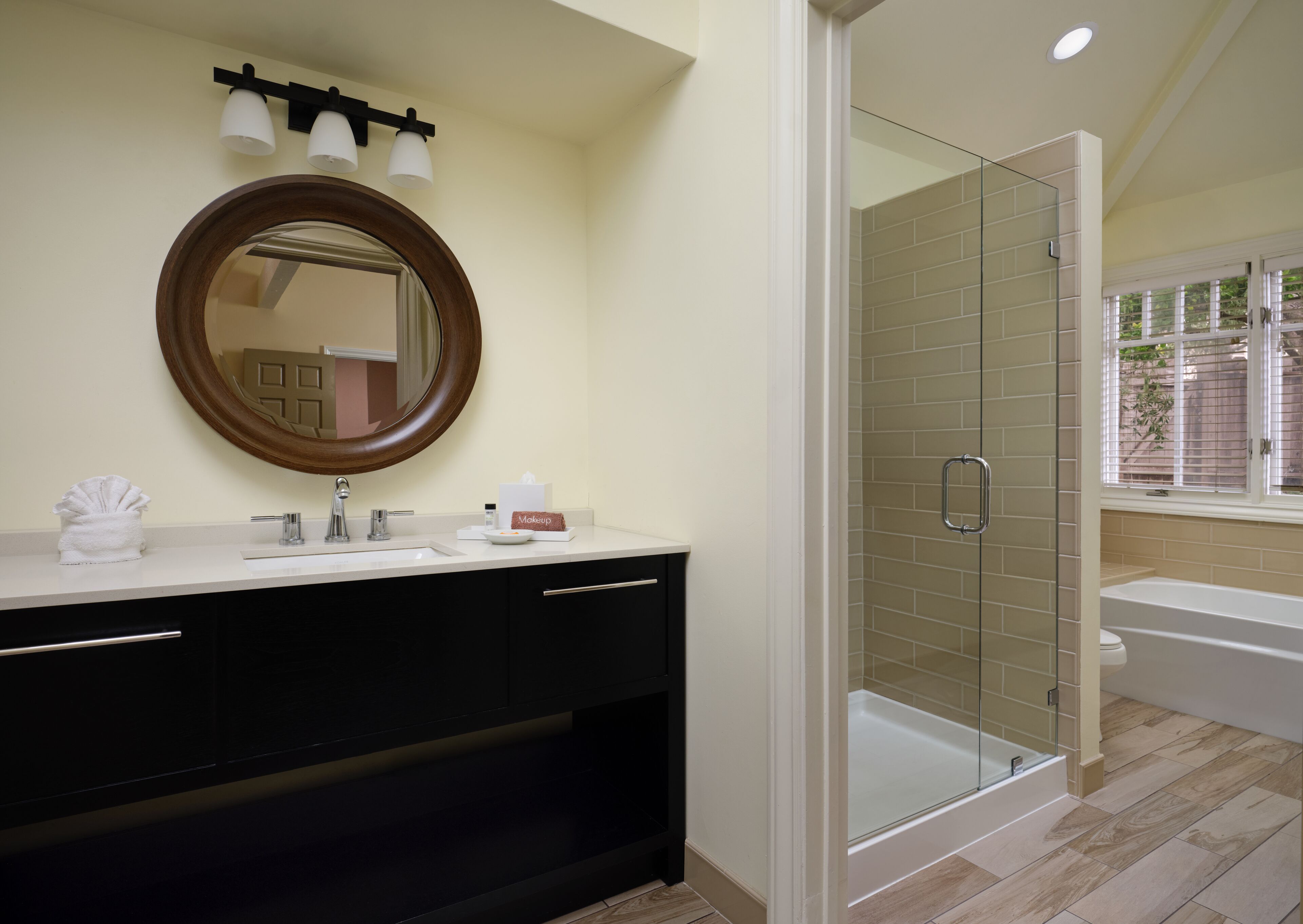 A bathroom with a large mirror, a sink, a vanity, a shower with glass doors, and a bathtub.